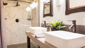 Un baño moderno con dos lavamanos, ducha y espejo.