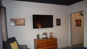 A bedroom with a TV, a dresser, a chair, and a bed.
