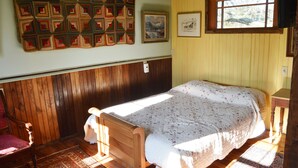 Une pièce avec un lit en bois, une chaise, un tapis à motifs et une tapisserie murale matelassée.