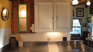 Une cuisine avec des meubles en bois, un plan de travail en acier inoxydable et une fenêtre avec des rideaux.