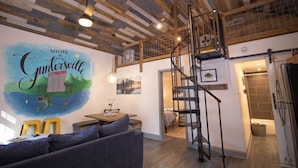 Un salon moderne avec un plafond en bois, un coin repas et un escalier menant à une mezzanine.