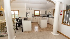 A spacious kitchen with white cabinetry, a central island, and a dining area with a table and chairs. - Oceanside, Pool, Hot Tub, Close to Beach, OH1, Silver Sandcastle (Corolla)