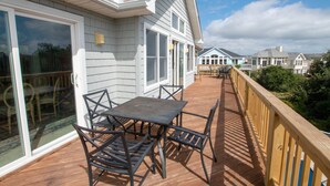 A wooden deck with a table and chairs, overlooking a residential area with houses. - Oceanside, Pool, Hot Tub, Close to Beach, OH1, Silver Sandcastle (Corolla)