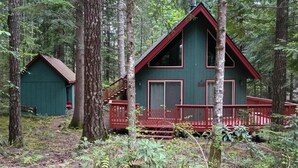 A cabin with a red deck, surrounded by trees.