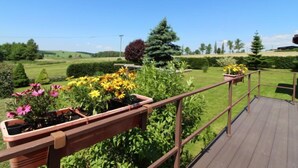 A wooden deck with a metal railing overlooking a landscaped garden with various plants and flowers. - Rokytnice v Orlických horách by Interhome (Rokytnice v Orlickych horach)