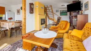 A cozy living room with a wooden dining table, yellow sofa, and a staircase. - Rokytnice v Orlických horách by Interhome (Rokytnice v Orlickych horach)