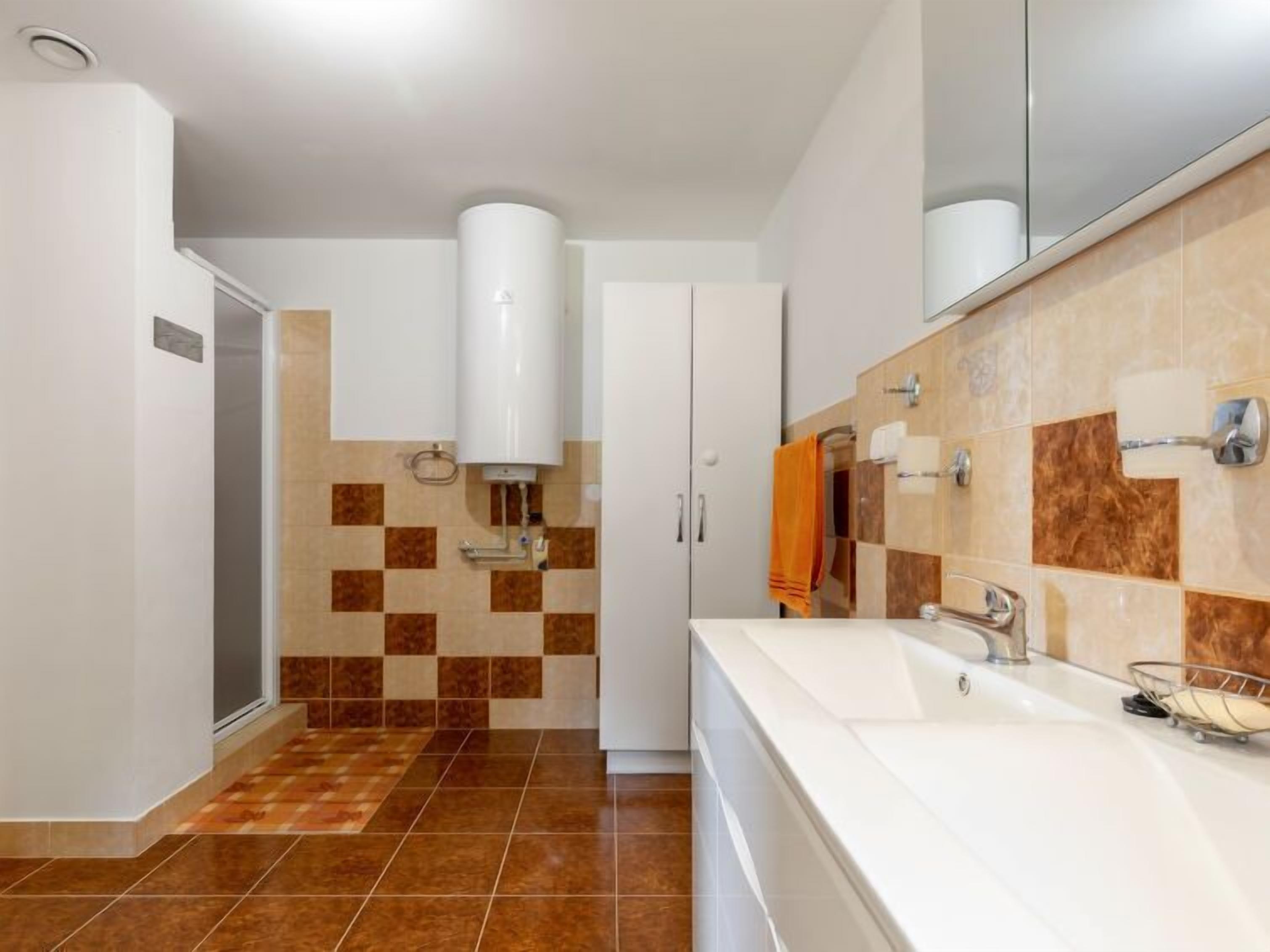 A modern bathroom with a white sink, a mirror, and a towel rack.