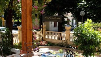 Eine Terrasse mit Tisch und Stühlen, umgeben von Grünpflanzen und einem Schild mit der Aufschrift 'Phil Chateau'.