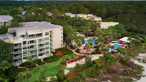 A hotel with multiple floors, a swimming pool, and surrounding greenery. - Hilton Head | Family Island Stay | Pool + Beach | 2BR Condo (Hilton Head Island)