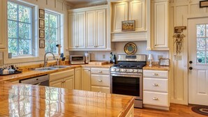 A spacious kitchen with white cabinetry, a large island, and a built-in oven. - Magazine Worthy. Two Blocks From Main Street.| Sweetwood Cottage (Highlands)