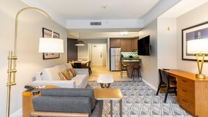 A compact living space with a sofa, a coffee table, a desk, and a kitchenette.