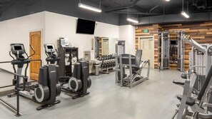 Une salle de sport équipée de machines de cardio, de matériel de musculation et d’haltères.