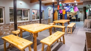 Restaurante com mesas e bancos de madeira, paredes de pedra e lareira de pedra.