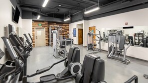 Un gimnasio moderno con diversas máquinas de ejercicio, un panel decorativo de madera y un interior limpio y bien iluminado.