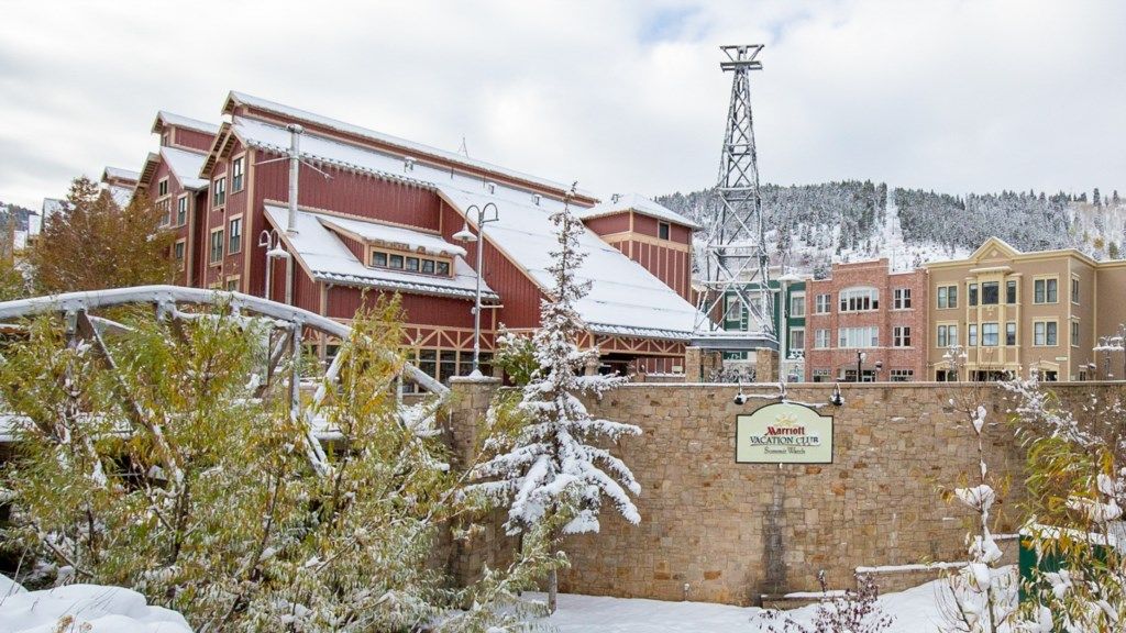 Un hotel Marriott con entrada de pared de piedra, un paisaje cubierto de nieve y una montaña al fondo.