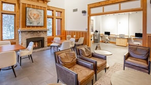 Un vestíbulo amplio con chimenea, asientos cómodos y una zona de recepción con computadoras y una caja registradora.
