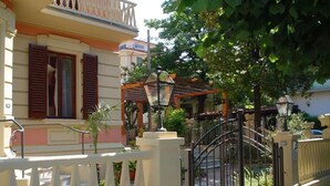 Un immeuble résidentiel doté d’une entrée sécurisée, d’un balcon et d’un jardin agrémenté de plantes en pot.