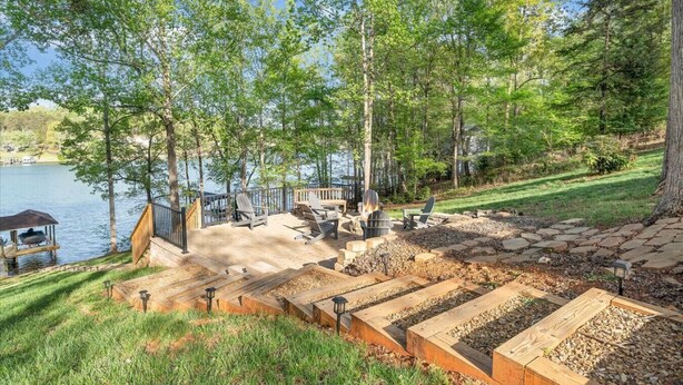 A lakeside deck with Adirondack chairs, a fire pit, and a dock with a boat. - Almost There- Fire pit, dog friendly sleeps 6 (Moneta)