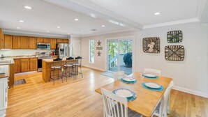 A spacious kitchen with wooden cabinets, a dining area with a wooden table and chairs, and a view of a deck through glass doors. - Almost There- Fire pit, dog friendly sleeps 6 (Moneta)