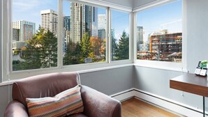 A corner room with large windows, a brown leather chair, and a small wooden table. - 20% Off July |City View + Parking |Walk to Downtown - Near Convention Center, Theaters & Stadiums (Seattle)