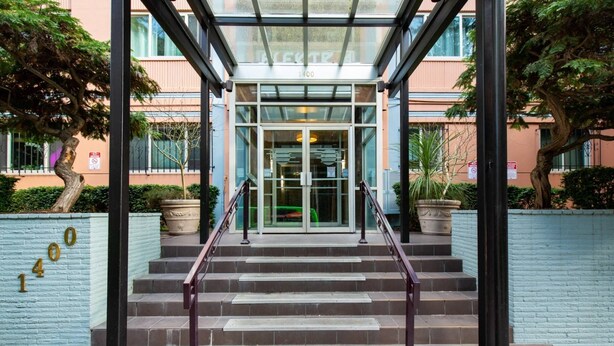 A hotel entrance with a glass door, a staircase with metal railings, and a blue brick wall with the number 1400. - 20% Off July |City View + Parking |Walk to Downtown - Near Convention Center, Theaters & Stadiums (Seattle)