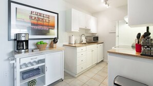 A modern kitchen with white cabinets, a coffee machine, a microwave, and a sink. - 20% Off July |City View + Parking |Walk to Downtown - Near Convention Center, Theaters & Stadiums (Seattle)