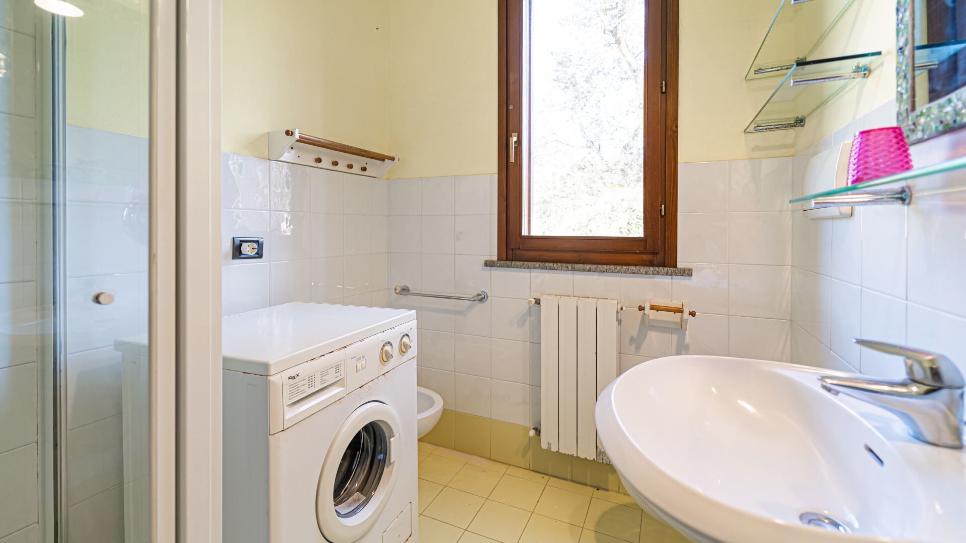 Un baño pequeño con lavadora, un lavabo y una ventana.