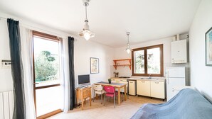A compact kitchen with a dining area, a single computer, and a bed. - APP.TI LA BAIA BAGNAIA - BILOCALE ROSMARINO (Portoferraio)