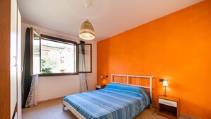 A bedroom with a bed, a window, a nightstand, and a hanging light fixture. - APP.TI LA BAIA BAGNAIA - BILOCALE ROSMARINO (Portoferraio)
