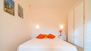 Une chambre à coucher comprenant un lit, deux lampes fixées au mur, une table de chevet et une armoire.