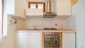 Prepare meals with ease in this functional kitchen featuring a gas stove, oven, and range hood.