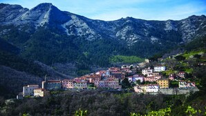Un village perché sur une colline, avec des bâtiments aux couleurs vives, niché au pied d’une montagne.
