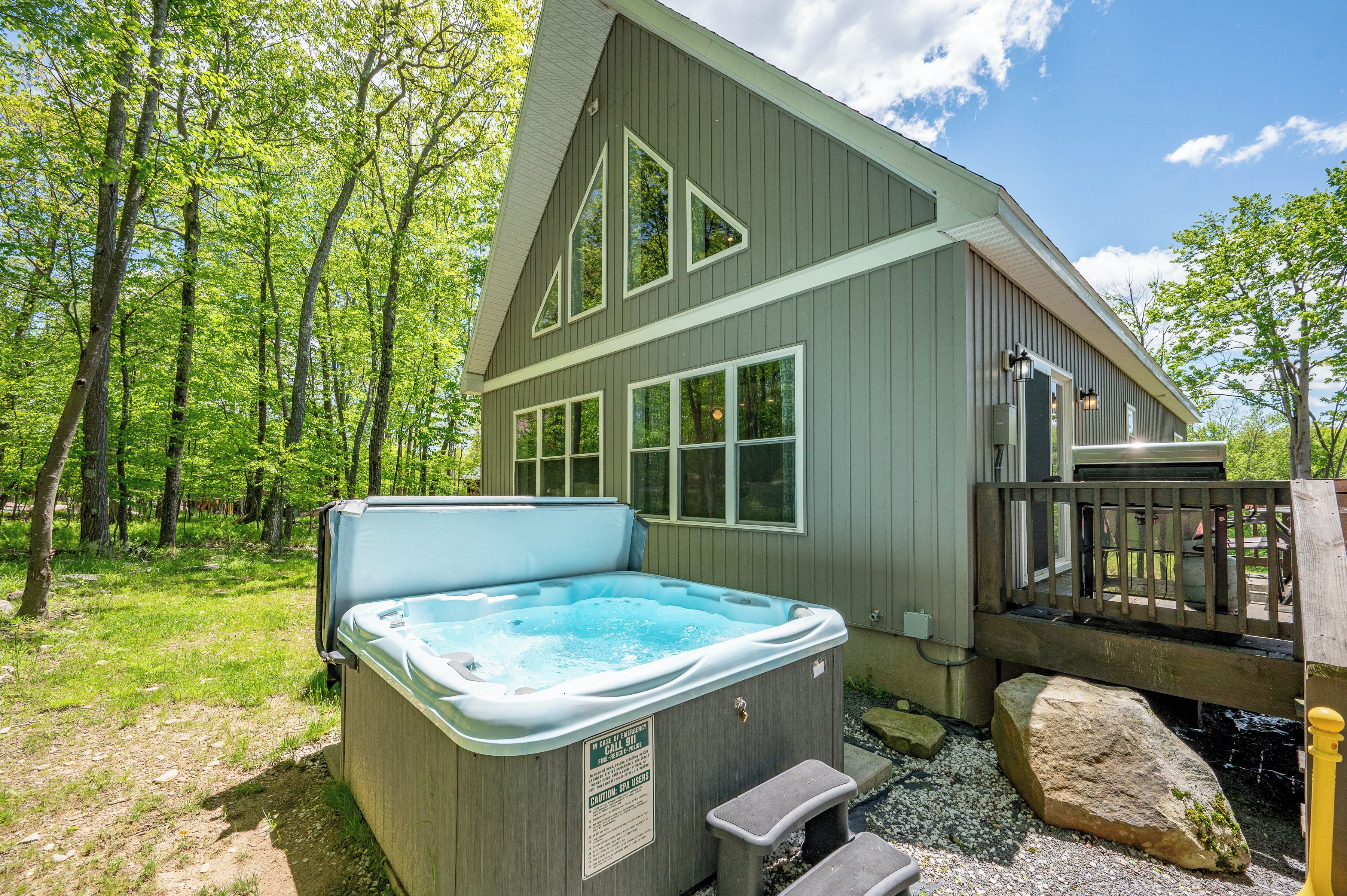 A spa hot tub outside a wooden building with a deck and a wooden railing.