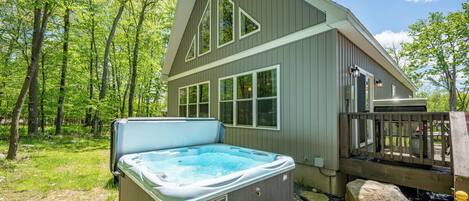 A spa hot tub outside a wooden building with a deck and a wooden railing.