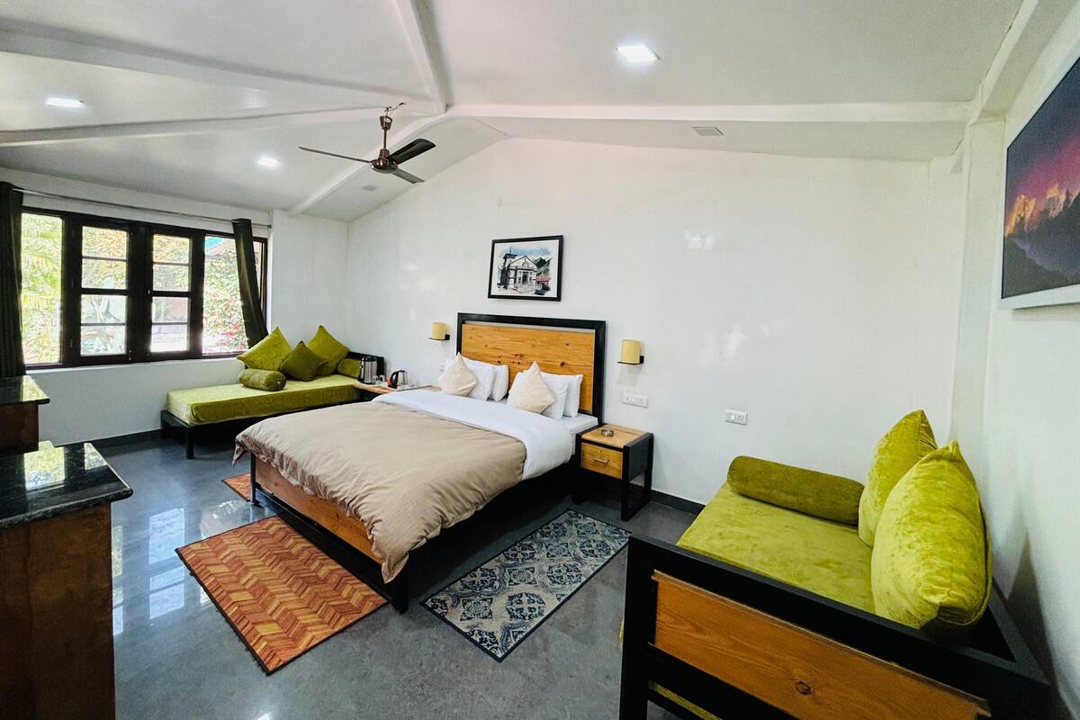 A bedroom with a bed, two sofas, a desk, and a ceiling fan.
