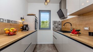 A modern kitchen with a window, a coffee machine, and a fruit bowl.