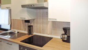 Une cuisine moderne dotée d’une plaque de cuisson à induction noire, d’un évier en acier inoxydable et d’une machine à café.