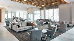 A spacious lobby with a modern design, featuring a mix of seating areas and a large window providing natural light. - AC Hotel by Marriott Tuscaloosa Downtown (Tuscaloosa)