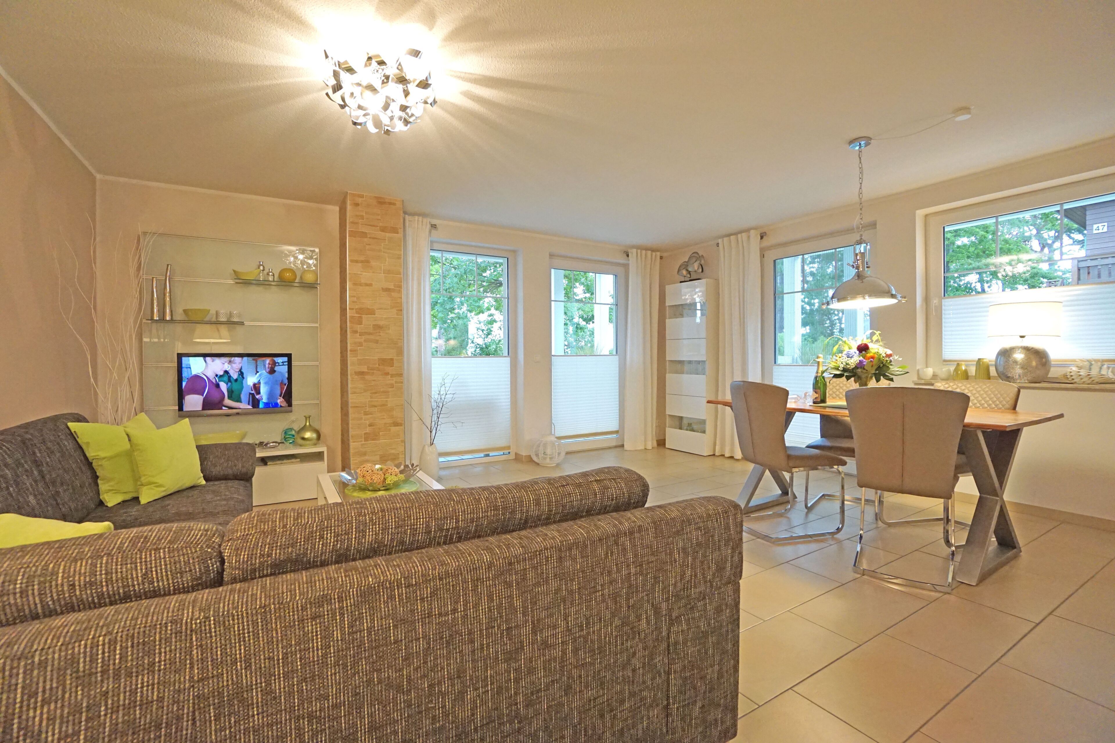 A living room with a sofa, TV, and dining area with chairs and a table.
