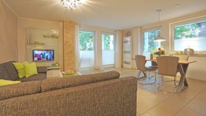 Ein Wohnzimmer mit Sofa, Fernseher und Essbereich mit Stühlen und Tisch.