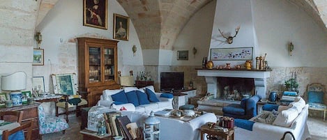 Una sala de estar acogedora con chimenea, asientos cómodos y techo de piedra.