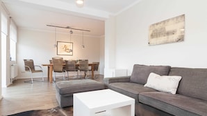 A modern living room with a grey sofa, a white coffee table, and wicker chairs. - Haus Düne 9, Deutschland (Hörnum (Sylt))