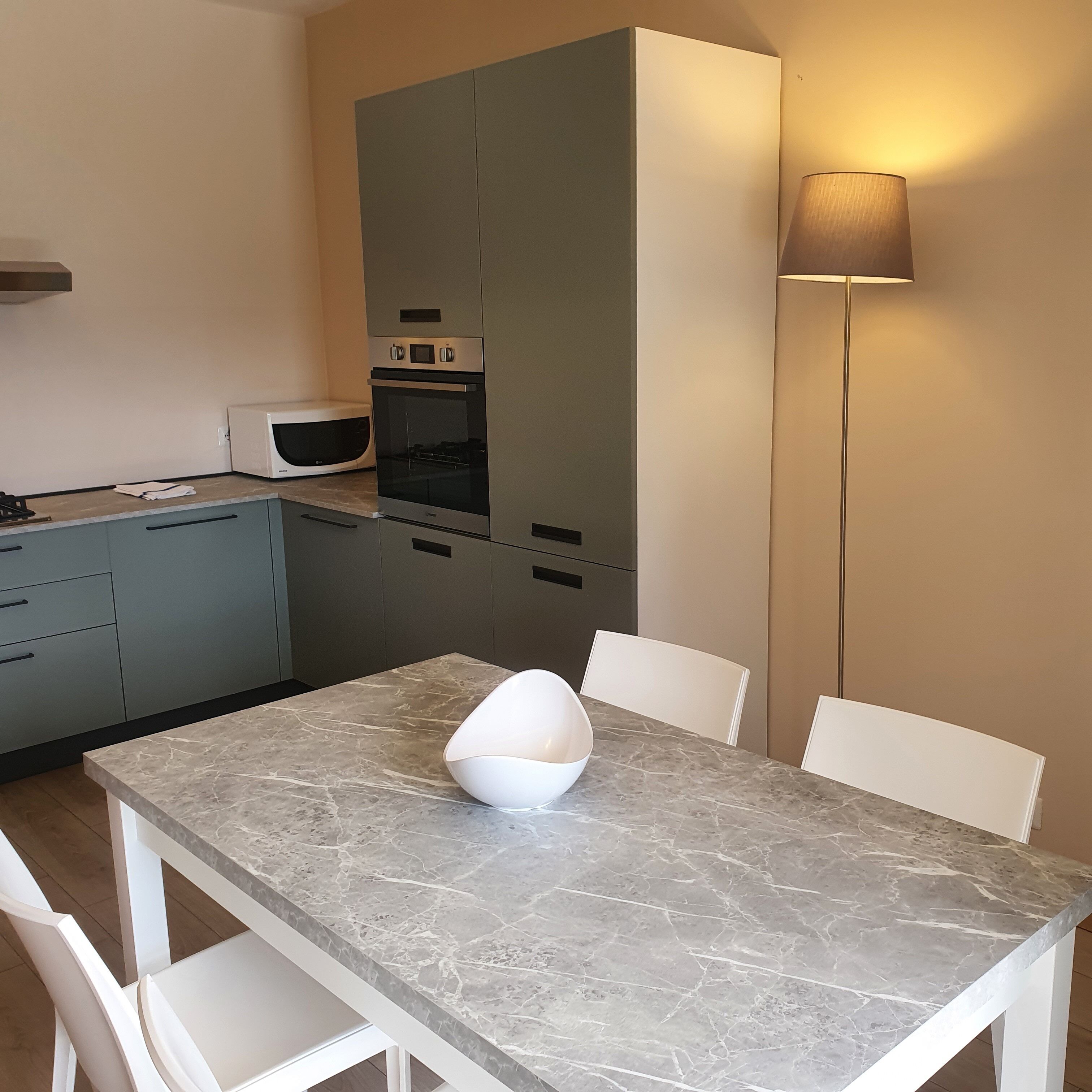 Une cuisine compacte équipée d’un four à micro-ondes, d’un four traditionnel et d’une table avec des chaises.