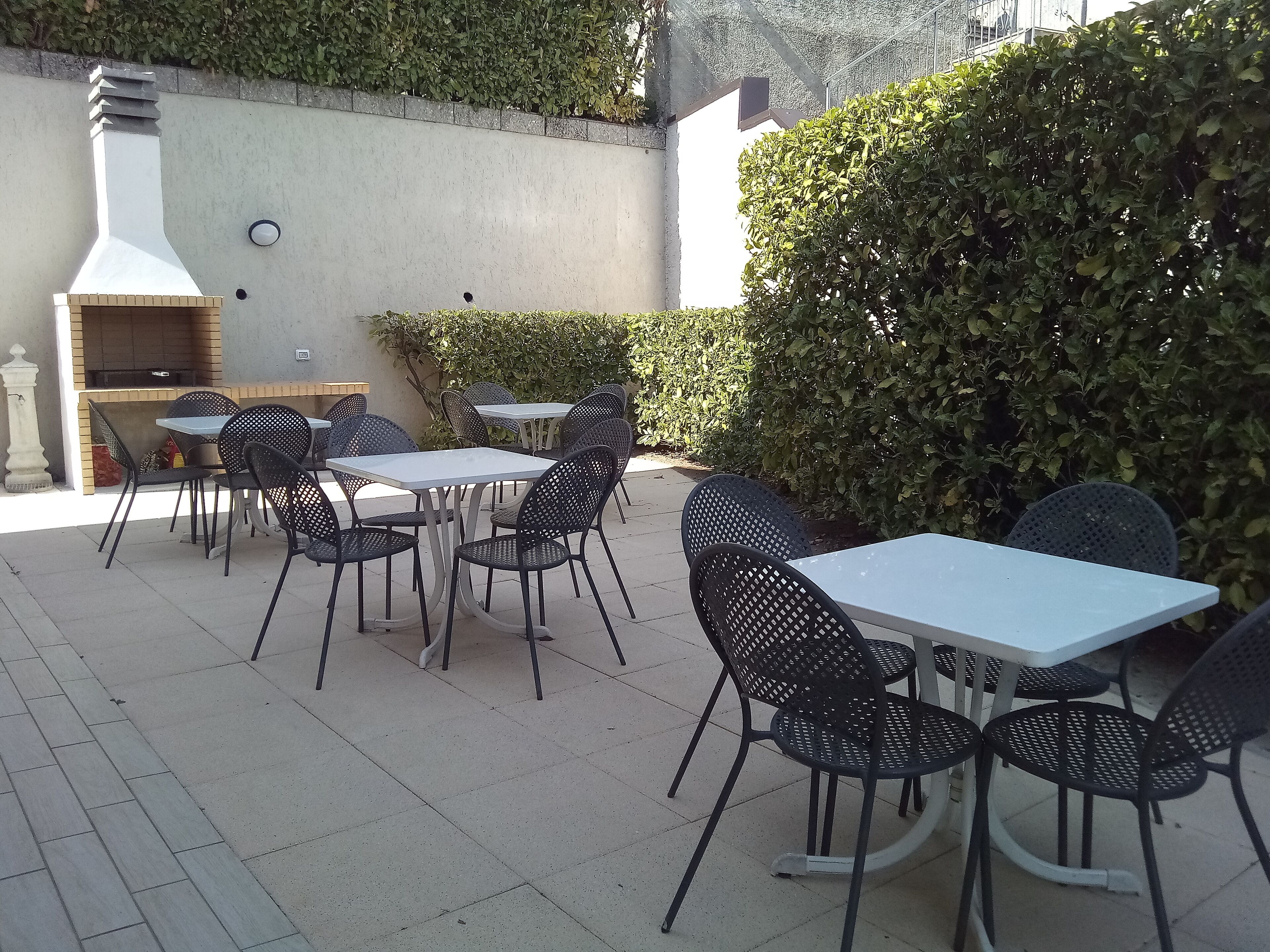 Un patio al aire libre con mesas y sillas, una parrilla y una pared con chimenea.