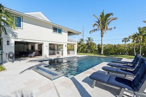 Et hus med swimmingpool, liggestole og en patio.