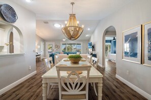 A dining area with a white table, chairs, and a central chandelier.