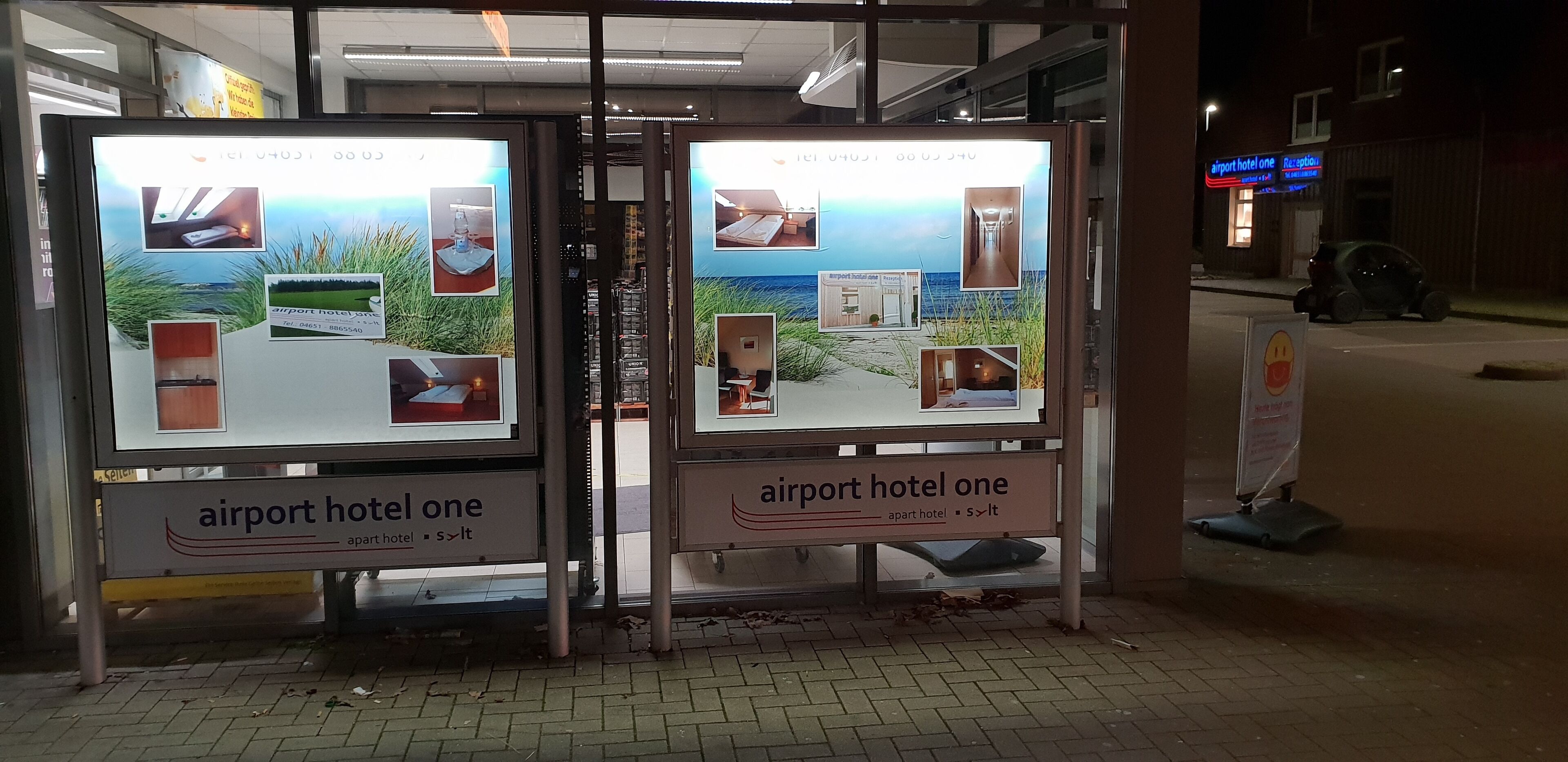 A set of illuminated advertisement panels for an airport hotel, featuring images of the hotel interior, a beach view, and a reception area.
