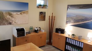 A hotel room with a desk, printer, coffee maker, and a view of the beach. - Airport Hotel One (Sylt)