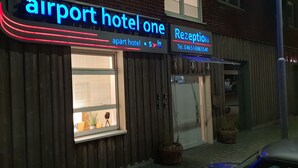 An airport hotel with a reception area, a window with blinds, and a wicker basket outside. - Airport Hotel One (Sylt)