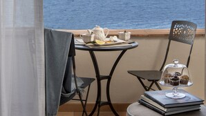 A balcony with a table set for tea, a chair, and a view of the sea. - Villa Galidia with Jacuzzi, Sea View, Garden and Air Conditioning (Sorrento)